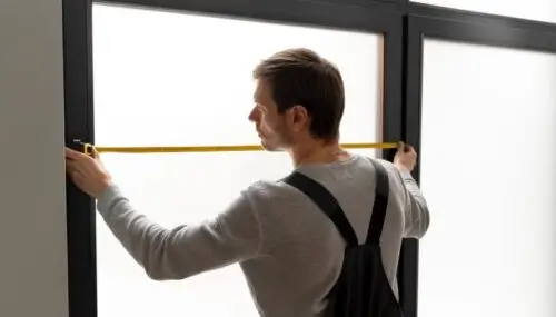 Handyman taking window measurement